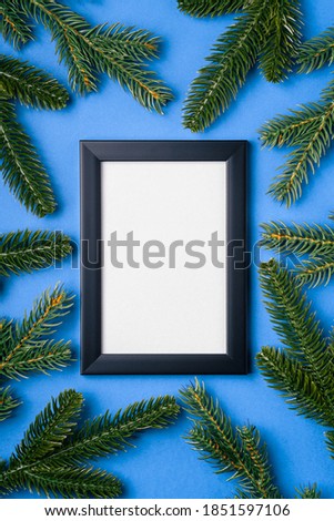 Christmas composition with empty picture frame. Fir branches decorations. Mock up greetings card template