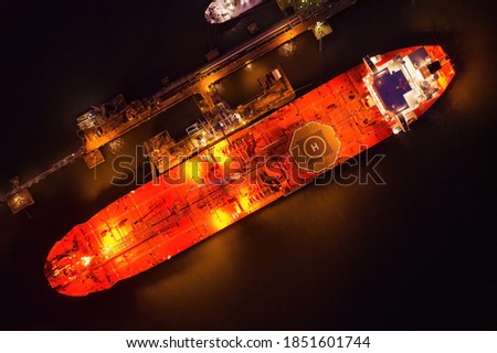 Crude oil shuttle tanker docked at night wtih light on creating an atmospheric glow with space for text. Royalty-Free Stock Photo #1851601744