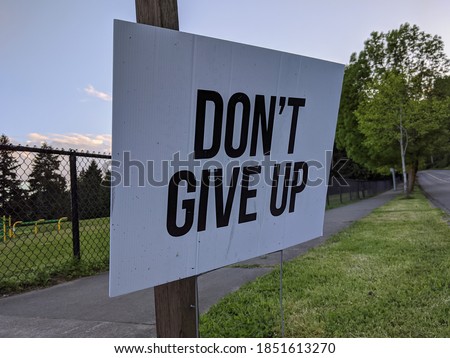 Angled view of a Don't Give Up motivational sign in a yard during the COVID-19 pandemic