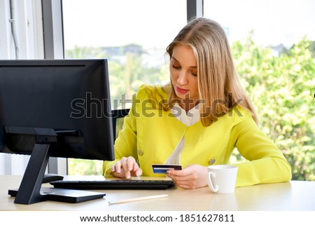 The businesswoman was shopping online using a desktop computer and she paid with a credit card.