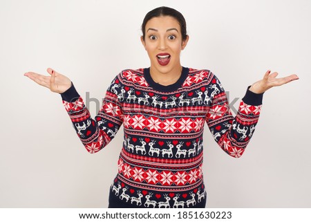 Beautiful arab girl wearing christmas sweater over isolated white background celebrating crazy and amazed for success with arms raised and open eyes screaming excited. Winner concept