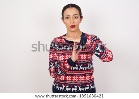 Beautiful arab girl wearing christmas sweater over isolated white background being upset showing a timeout gesture, needs stop, asks time for rest after hard work, demonstrates break hand sign
