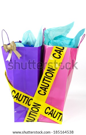 Caution tape over colorful shopping bags on white background, balancing the debt and managing home finances concept image 