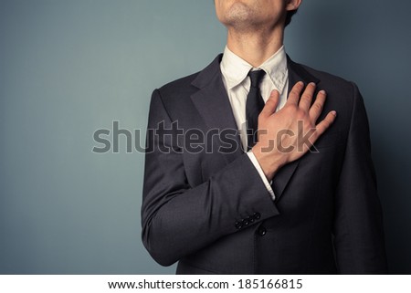 Young businessman is swearing allegiance with his hand on his chest Royalty-Free Stock Photo #185166815