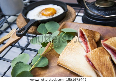 Image of outdoor breakfast of fried egg and strawberry jam hot sandwich
