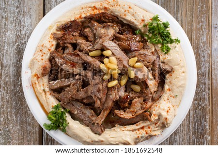 A top down view of a plate of hummus topped with beef shawarma.