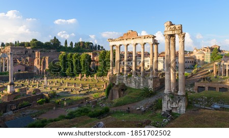 Perspective of the Roman Forum ancient ruins and Colosseum ampitheater, in Rome, Italy, with temple of Saturn, temple of Vesta, Basilica of Maxentius, Arch of Titus and Palatine Hill at sunrise