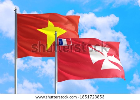 Wallis And Futuna and Vietnam national flag waving in the windy deep blue sky. Diplomacy and international relations concept.