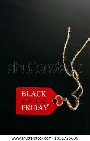 Black friday shopping sale concept. Text on red tag on black wooden background. Vertical image, copy space.