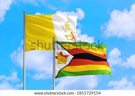 Zimbabwe and Vatican City national flag waving in the windy deep blue sky. Diplomacy and international relations concept.