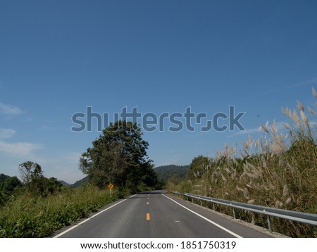 A view on the curved road, on the road overlooking the traffic sign. With far side, picture Is a view of the mountains and the sky that can be seen comfortably On the day of our trip
