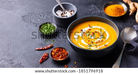 Pumpkin soup with spices in black bowl. Dark background. Close up. Copy space. Royalty-Free Stock Photo #1851796918