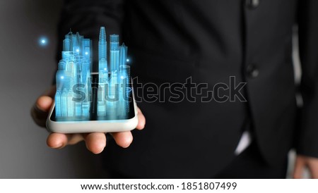 Businessman holds 3D city model showing augmented reality technology . Futuristic urban hologram screen in concept of virtual internet of things and global network connection .