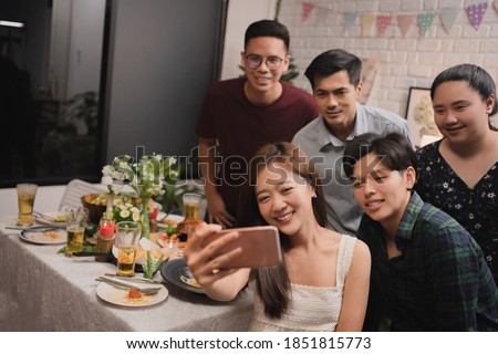 Group of Asian friends taking a selfie while having dinner after work.