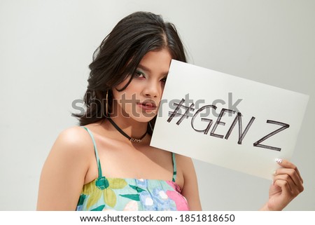 Trendy teenager show a text board with the text " gen z", she has rainbow eyeshadow and croptop tropical pattern Royalty-Free Stock Photo #1851818650