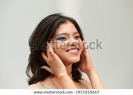 Make-up and cosmetics. Portrait of a beautiful smiling girl with bright colorful make-up on a white background
