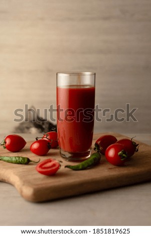 Tomato juice in a glass tall glass and a cat in the background. Selective focus, shallow depth of field. Studio shot.