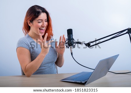 An emotional woman is broadcasting online on a laptop. Female radio presenter at the workplace
