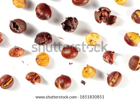 Roasted chestnuts in various stages of peeling, shot from the top on a white background, a flat lay