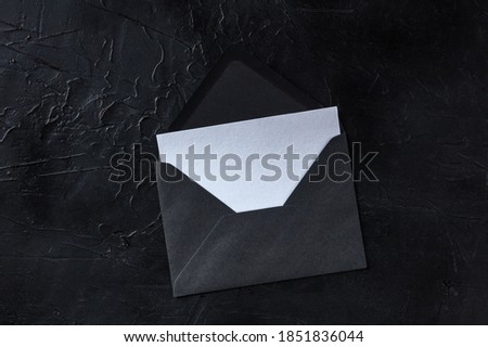 A greeting card in a black envelope mockup, shot from above on a dark background with copy space