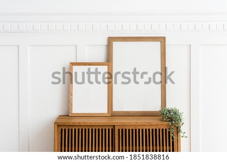 Two picture frames on a wooden sideboard