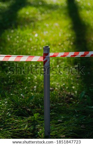 The barrier tape separates nature from humans. Forest and park zone is prohibited. The entrance to the beautiful sunlit lawn in the forest is closed. Respect for nature concept.