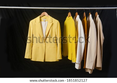 Row of different colorful suit  ,yellow, brown sweater, t on hanger-black background