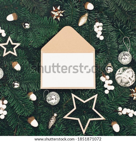 Christmas holiday winter New Year festive card. Empty craft card, Xmas silver festive decorations, mushrooms, acorns on Christmas tree branches background. Flat lay, top view, copy space.
