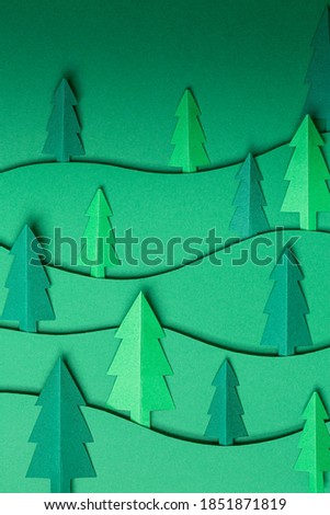 3D pop out Christmas trees paper artwork in green background. Christmas tree paper cutting design card. Top view. Flat lay