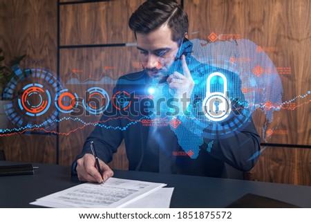 A man in office signing papers while talking mobile and lock icon hologram. Double exposure. Formal wear. Protection data.