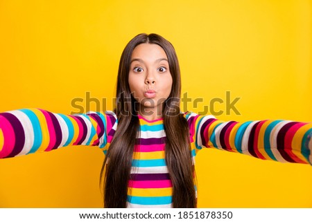 Photo of small girl make selfie send air kiss funny face wear striped shirt isolated yellow color background