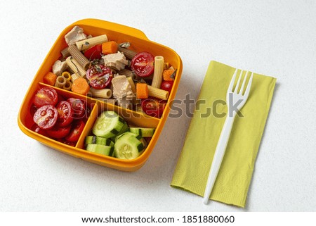 Lunch at work place healthy pasta with tuna, cherry tomatoes, carrot, cucumber in lunch box on work table. Home food for office concept