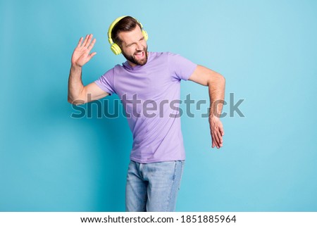 Photo portrait of bearded man enjoying music dancing wearing t-shirt jeans isolated on vivid blue color background