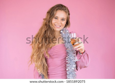 Young happy girl celebrates New Year and Christmas over pink background.