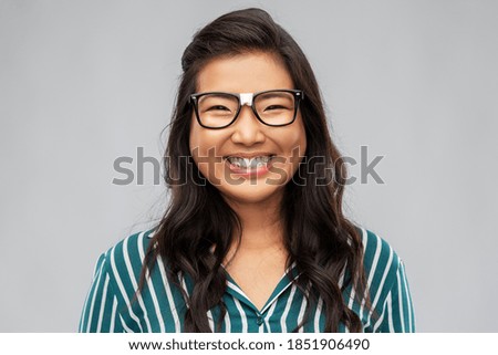 people, education and school concept - portrait of happy asian woman in broken glasses with patch or student over grey background