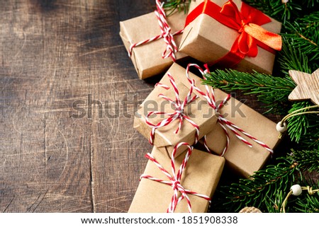 Gift boxes in craft paper. Christmas gifts under spruce branches on a brown wooden background. Сopyspace	