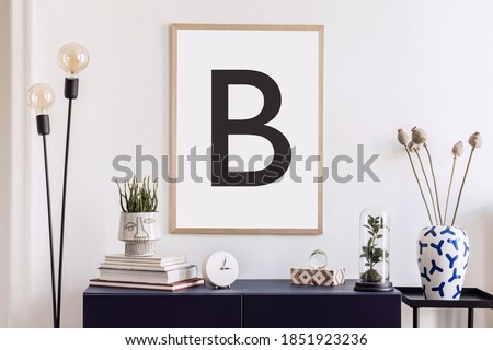 Stylish interior of living room with blue navy commode, mock up poster frame, decoration, book and elegant personal accessories in modern home decor. Template. 