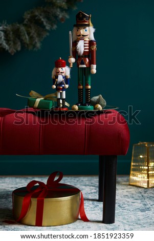 Christmas composition on the red velvet bench with decoration, gifts, wreath, nutcracker and accessories. Copy space. Red and green color. Template. 