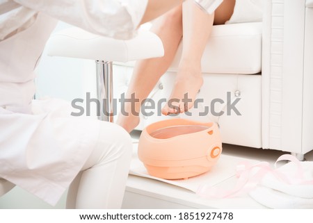 Wax bath for feet at beauty spa salon. Paraffin wax treatments for feet. Royalty-Free Stock Photo #1851927478