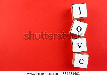 Vertically laid out word "love" by wooden cubes on red background