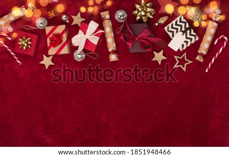 Christmas holiday winter New Year festive card. Xmas gold wooden decorations, gift boxes, candy canes on red textile background. Flat lay, top view, copy space