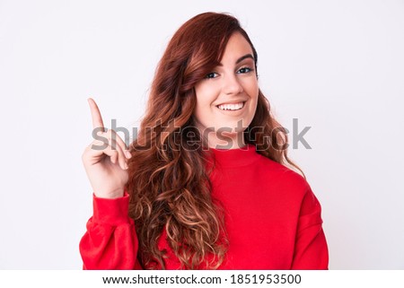 Young beautiful woman wearing casual clothes with a big smile on face, pointing with hand and finger to the side looking at the camera. 