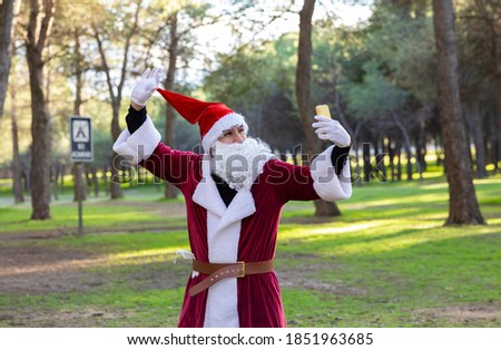 Santa Claus takes pictures with his mobile in the forest