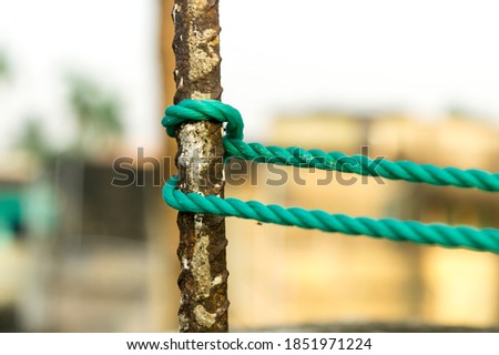 A rope is tied in a knot around a fence post, rope tied Hitch Knots on a rusty iron pole isolated from background.