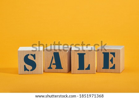 wooden blocks with the wordings SALE, isolated against yellow background.