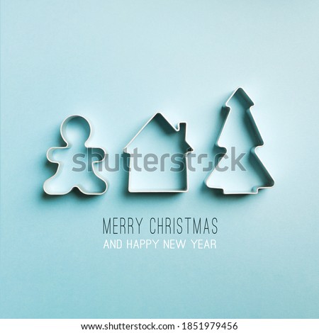 Christmas minimal blue background. cookie cutters tree, house, gingerbread man. text merry christmas and happy new year.