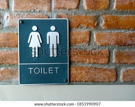 Toilet sign on bricked wall