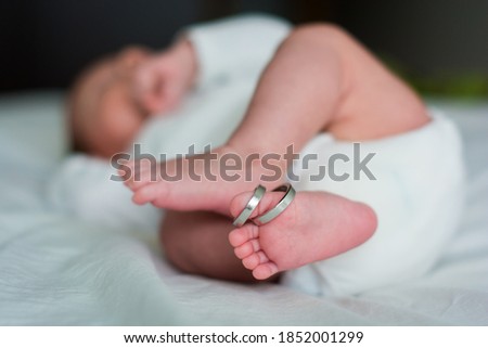 Feet of a newborn and his parents wedding rings. Legs of a newborn baby with mom and dad's wedding ring. Happy Family concept. Royalty-Free Stock Photo #1852001299