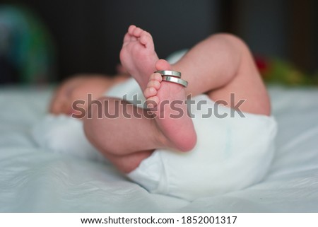 Feet of a newborn and his parents wedding rings. Legs of a newborn baby with mom and dad's wedding ring. Happy Family concept. Royalty-Free Stock Photo #1852001317