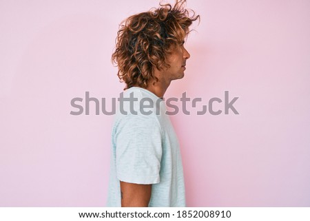 Young hispanic man wearing casual clothes looking to side, relax profile pose with natural face with confident smile. 